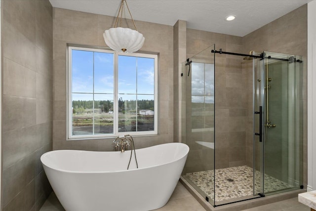 bathroom with a stall shower, a soaking tub, tile walls, tile patterned flooring, and a textured ceiling