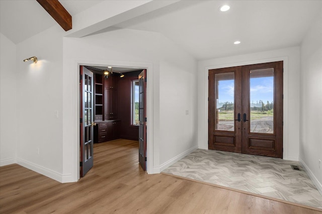 foyer entrance with french doors, healthy amount of natural light, baseboards, lofted ceiling, and light wood-style flooring