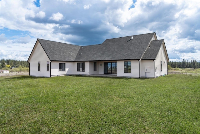 rear view of house with a lawn, roof with shingles, and a patio area