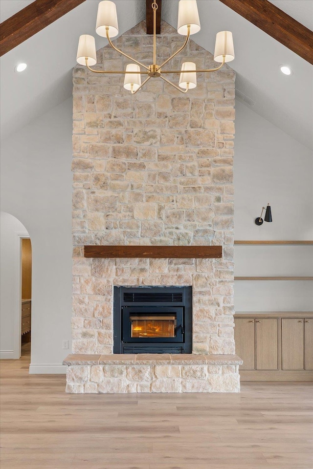 detailed view of wood finished floors, baseboards, beamed ceiling, arched walkways, and a fireplace