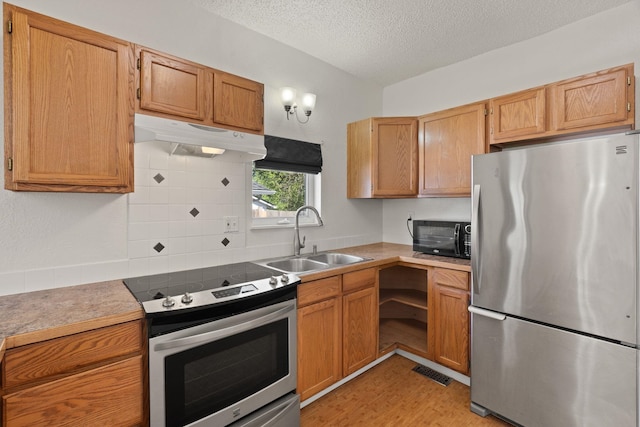 kitchen featuring a sink, a textured ceiling, visible vents, decorative backsplash, and appliances with stainless steel finishes