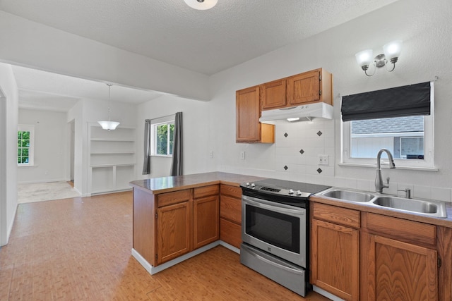 kitchen featuring under cabinet range hood, brown cabinetry, stainless steel electric range oven, a sink, and a peninsula