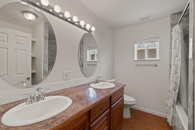 bathroom with toilet, visible vents, a sink, and double vanity