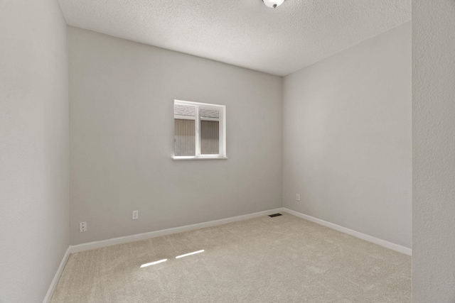 carpeted empty room featuring a textured ceiling and baseboards