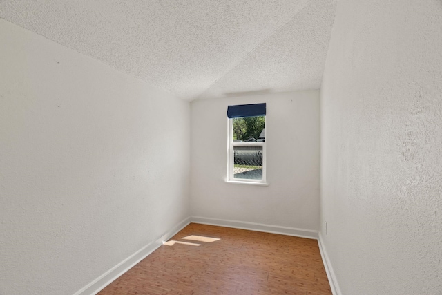 empty room with a textured ceiling, wood finished floors, and baseboards