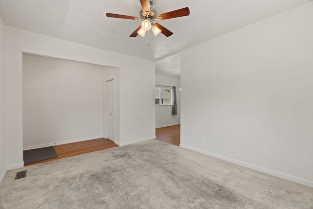 carpeted empty room featuring ceiling fan, a textured ceiling, baseboards, and visible vents