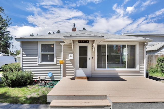 exterior space with a chimney, a deck, and fence