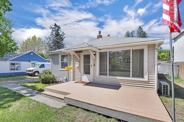 bungalow with fence, a wooden deck, and a chimney
