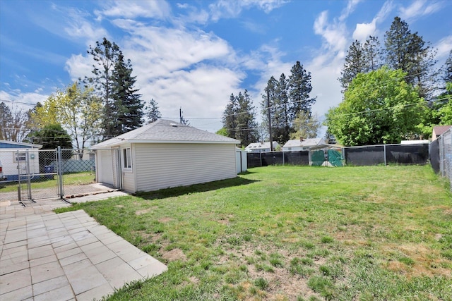 view of yard with an outbuilding, a garage, a fenced backyard, and a gate