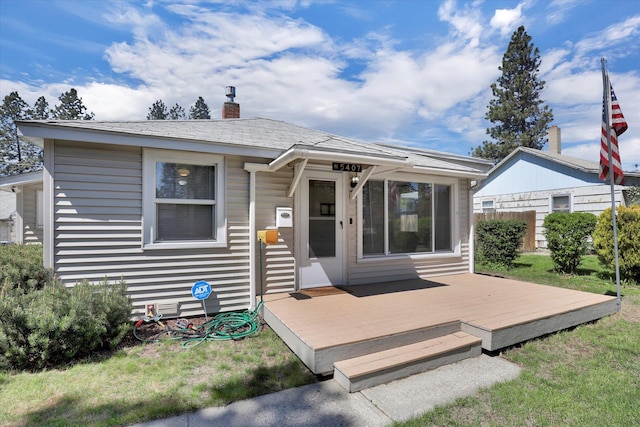 view of front of property with a front lawn, fence, a chimney, and a wooden deck