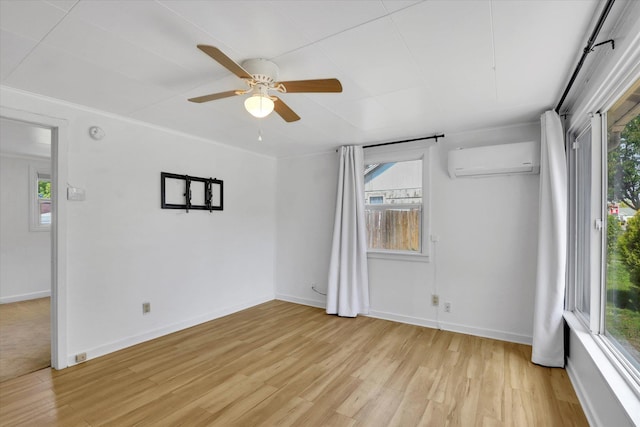 spare room with a wall mounted air conditioner, light wood-style floors, a wealth of natural light, and ceiling fan