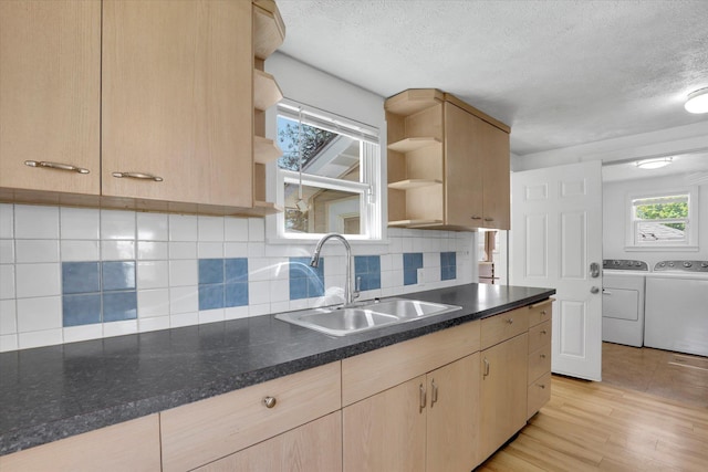 kitchen with a sink, a textured ceiling, light brown cabinetry, and washer and dryer