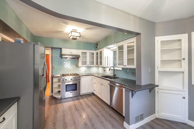 kitchen with wood finished floors, a sink, stainless steel appliances, visible vents, and under cabinet range hood