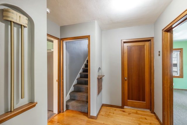 hallway with baseboards, stairs, and light wood finished floors