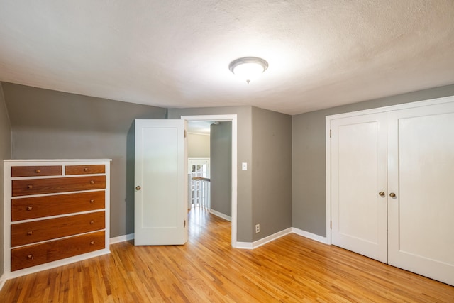 unfurnished bedroom with baseboards, light wood finished floors, and a closet