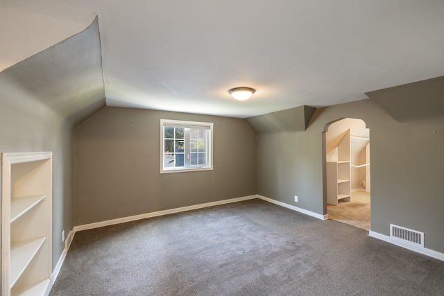 bonus room with carpet, baseboards, visible vents, vaulted ceiling, and arched walkways