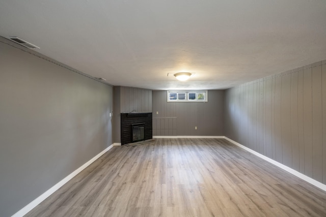 unfurnished living room featuring a fireplace, baseboards, visible vents, and wood finished floors