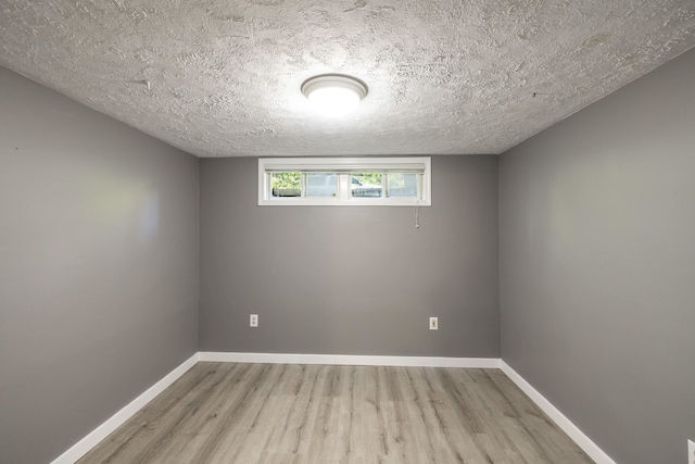 spare room featuring a textured ceiling, wood finished floors, and baseboards