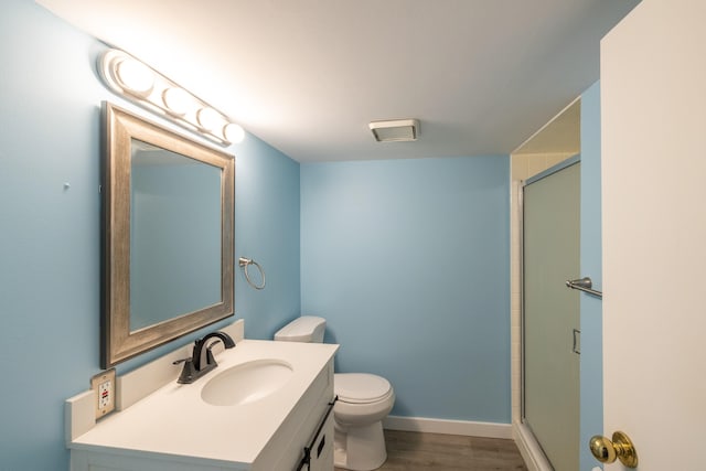 full bathroom featuring a stall shower, vanity, toilet, and wood finished floors