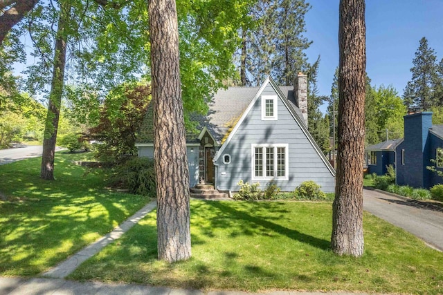 a-frame style home featuring a chimney and a front lawn