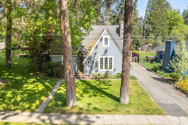 bungalow-style home featuring a front lawn and a chimney