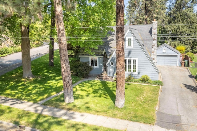 view of front of home with a chimney, an outdoor structure, a front lawn, and a garage