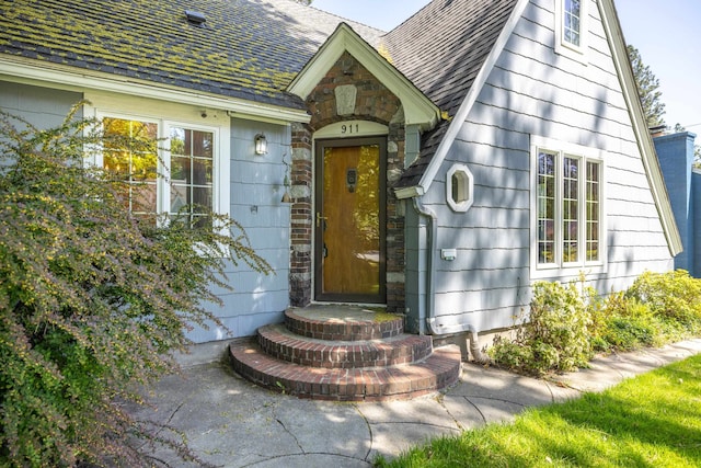 doorway to property with roof with shingles and stone siding