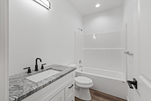 bathroom with toilet, wood finished floors, vanity, and  shower combination