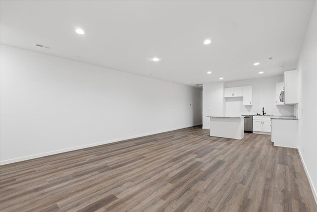 unfurnished living room featuring wood finished floors, a sink, visible vents, baseboards, and recessed lighting