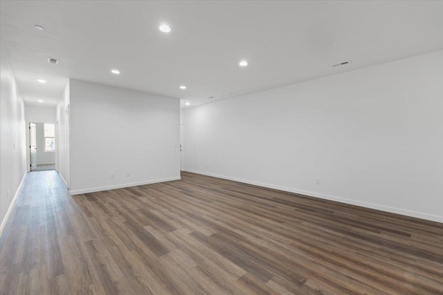 empty room with wood finished floors, baseboards, visible vents, and recessed lighting