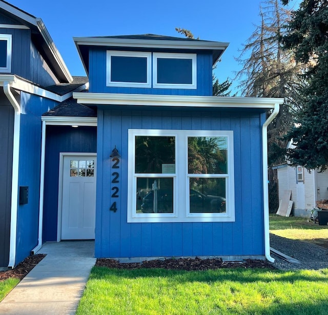 view of front of home featuring a front lawn and a shingled roof