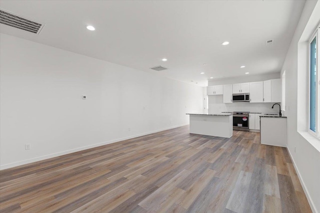 unfurnished living room featuring recessed lighting, light wood-type flooring, visible vents, and a sink