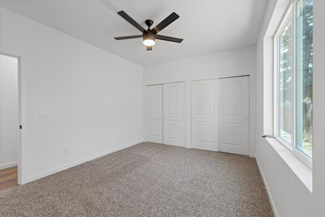 unfurnished bedroom featuring carpet flooring, multiple closets, and multiple windows