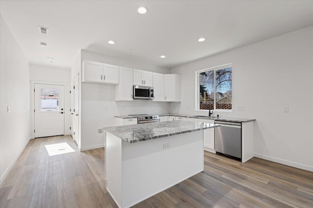 kitchen with light stone countertops, stainless steel appliances, light wood-style flooring, and white cabinets