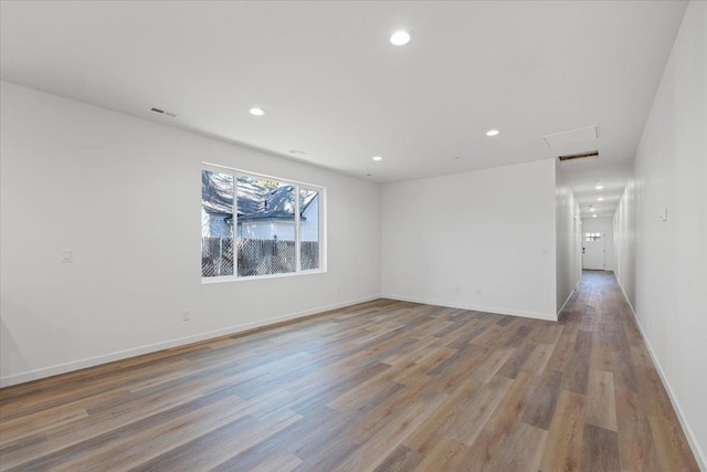 spare room with baseboards, recessed lighting, attic access, and light wood-type flooring