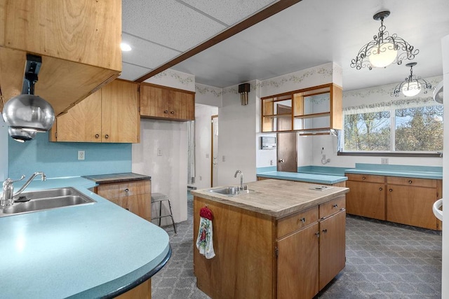 kitchen with pendant lighting, brown cabinetry, an island with sink, and a sink