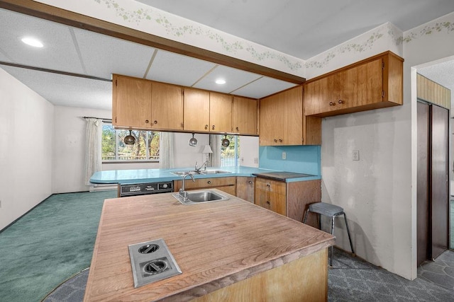 kitchen featuring a peninsula, dark colored carpet, brown cabinets, and a sink