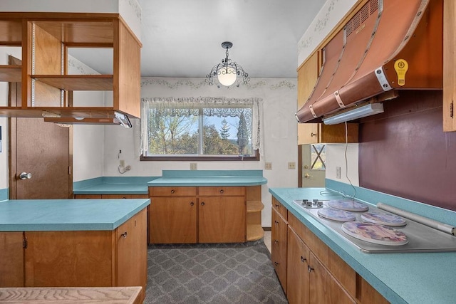 kitchen featuring brown cabinetry, white electric stovetop, under cabinet range hood, light countertops, and hanging light fixtures