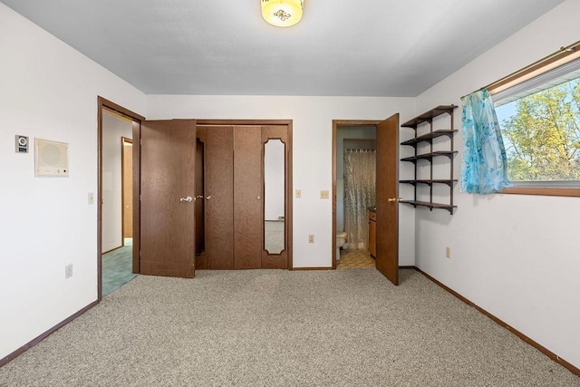 unfurnished bedroom with baseboards, ensuite bathroom, and carpet floors