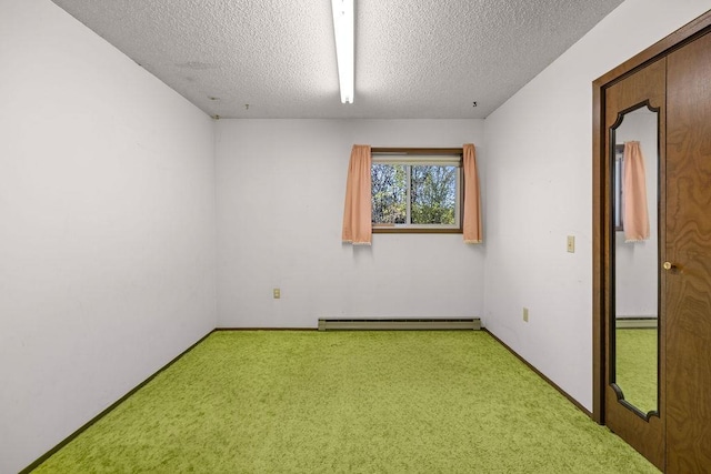 spare room with carpet, a textured ceiling, and a baseboard heating unit