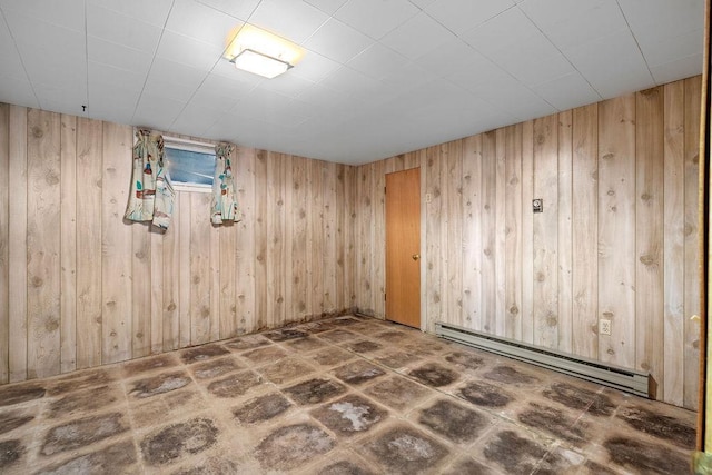 empty room featuring wooden walls and a baseboard heating unit