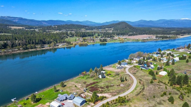 aerial view with a water and mountain view and a wooded view