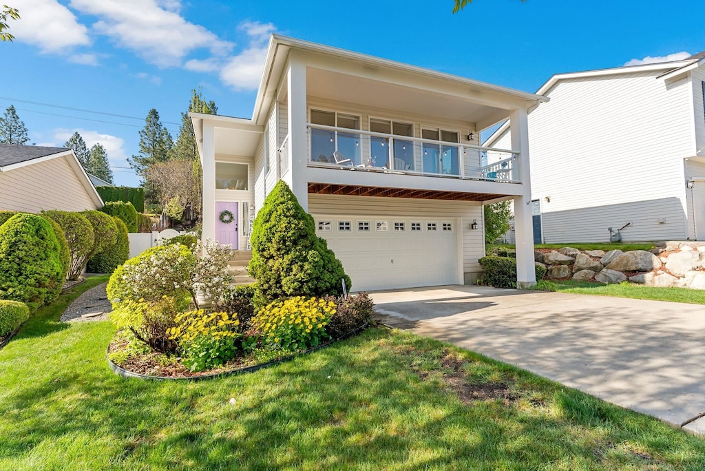 view of front of home featuring a front yard, driveway, a garage, and a balcony