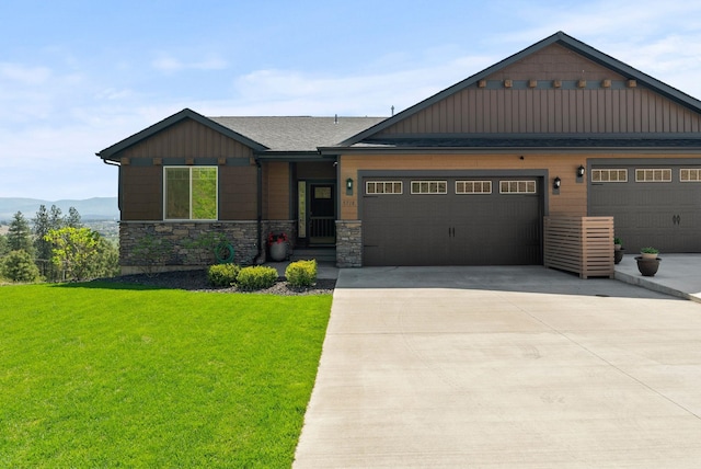 craftsman-style house featuring an attached garage, stone siding, board and batten siding, a front yard, and driveway