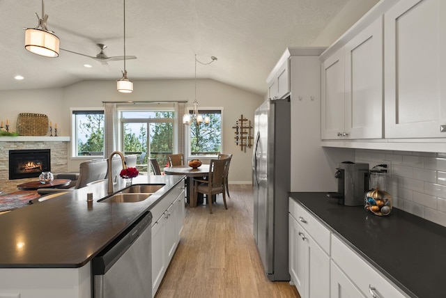 kitchen featuring a sink, lofted ceiling, stainless steel appliances, and dark countertops