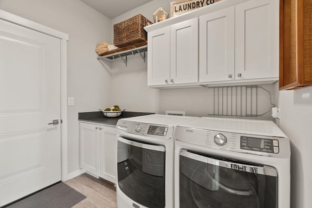 laundry room featuring cabinet space, washer and clothes dryer, and light wood-style floors