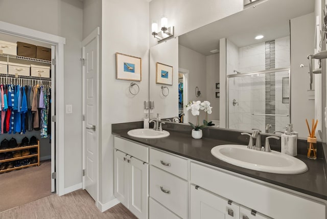 full bath with a sink, double vanity, a spacious closet, and a shower stall