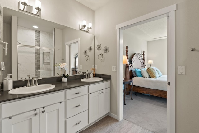 full bath with ensuite bathroom, wood finished floors, a shower stall, and a sink