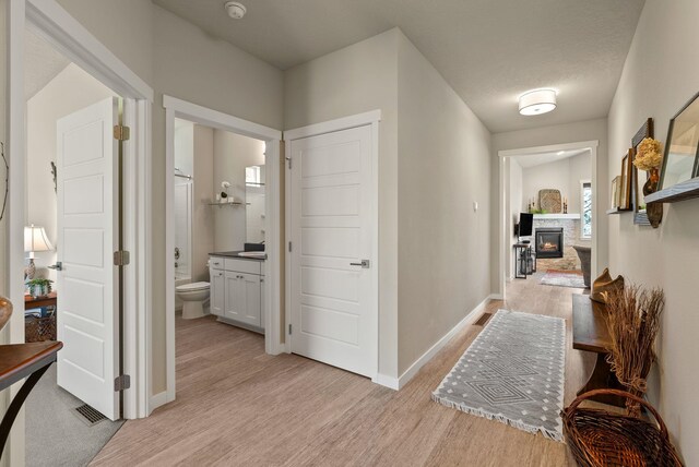 corridor with baseboards and light wood-style flooring