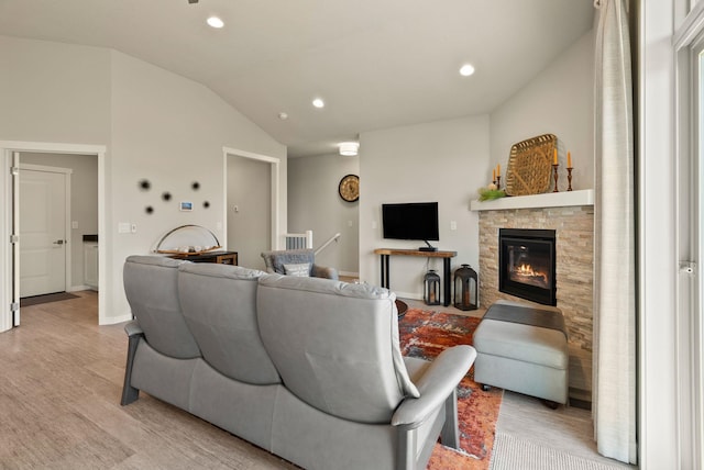 living area featuring light wood finished floors, a fireplace, baseboards, vaulted ceiling, and recessed lighting